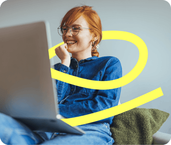 A redheaded woman smiles as she looks at a laptop and a yellow ribbon surrounds her implying she is engaged in the learning experience and excited about adopting AI tools