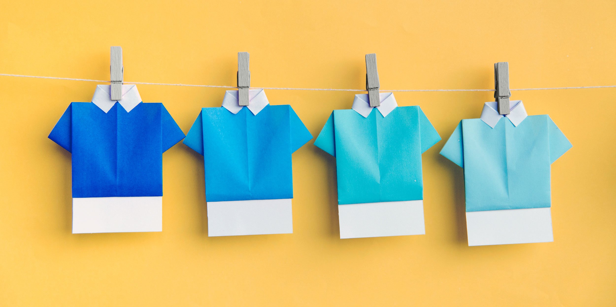 Four blue origami shirts pinned on a clothesline 