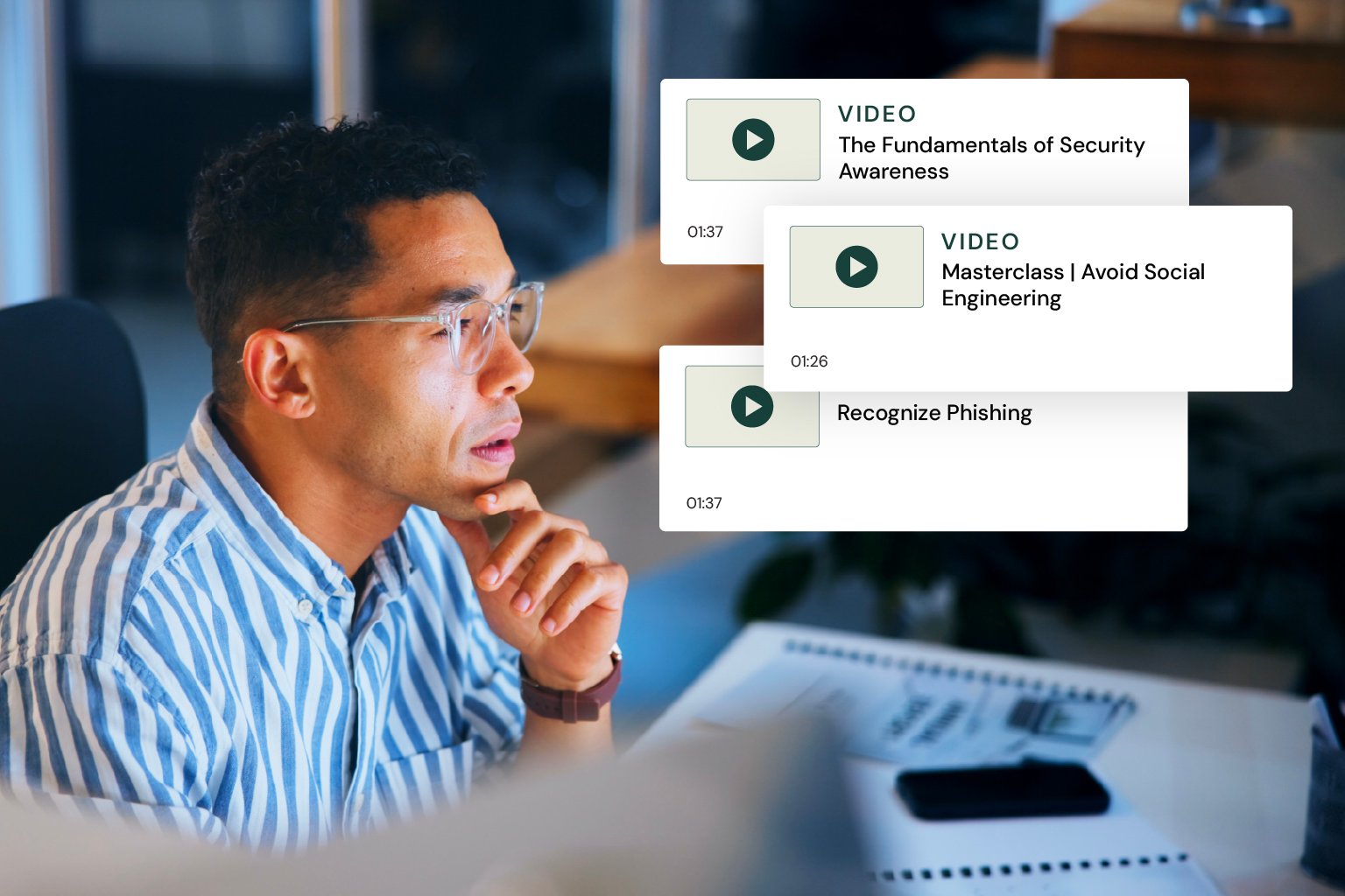 A man is working and on screen visuals represent security awareness training content he is enrolled in