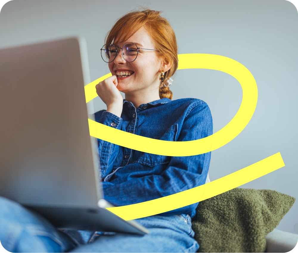 A redheaded woman smiles as she looks at a laptop and a yellow ribbon surrounds her implying she is engaged in the learning experience and excited about adopting AI tools